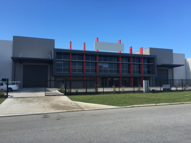 Exterior shot of large commercial office and warehouse complex, finished in dark grey with red accents