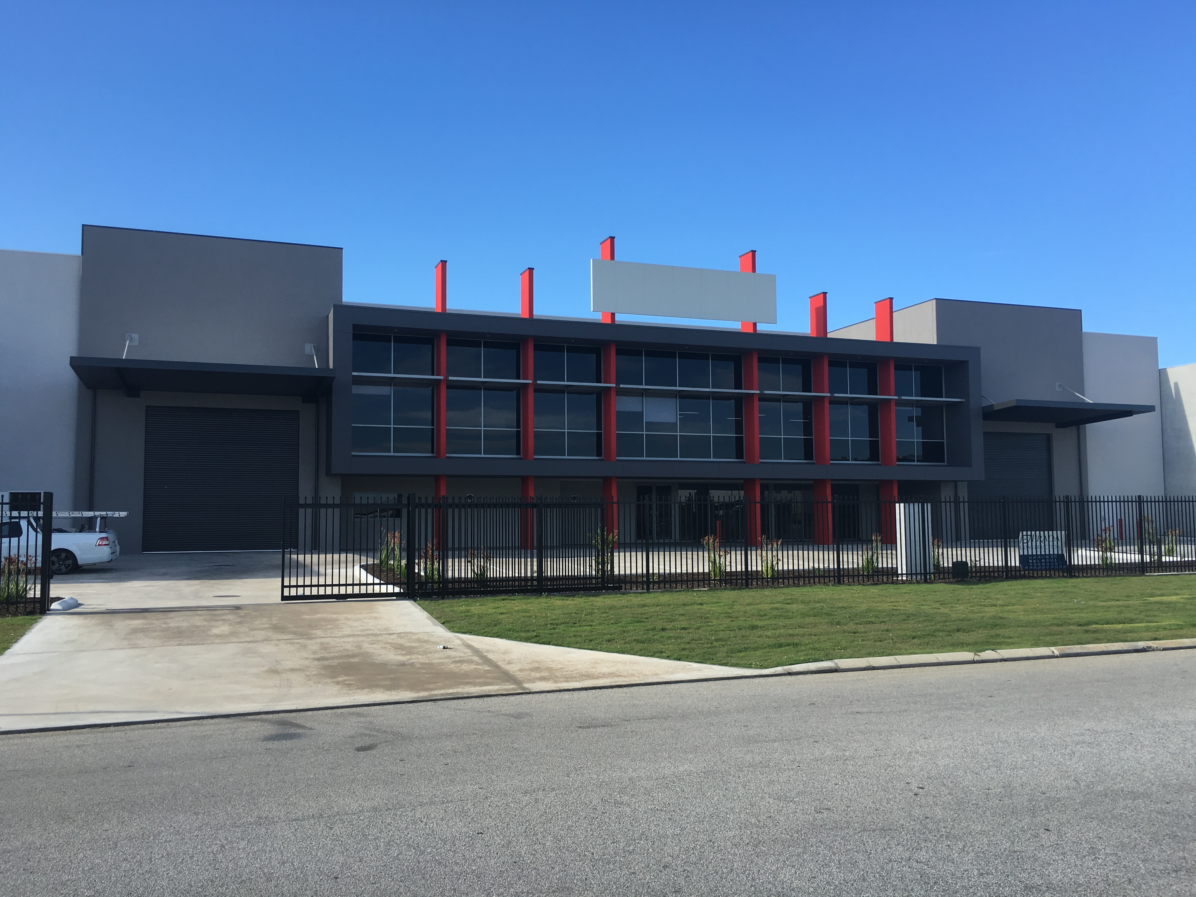 Exterior shot of large commercial office and warehouse complex, finished in dark grey with red accents