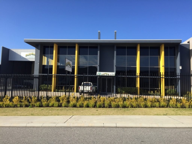 Exterior shot of large commercial office painted in dark grey and finished with yellow accents