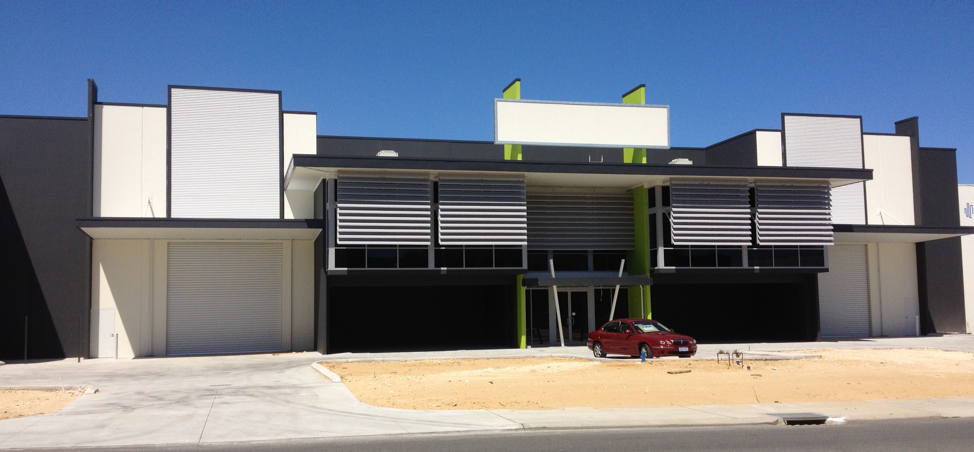 Exterior of large commercial warehouse units, painted in dark grey with lime accents.