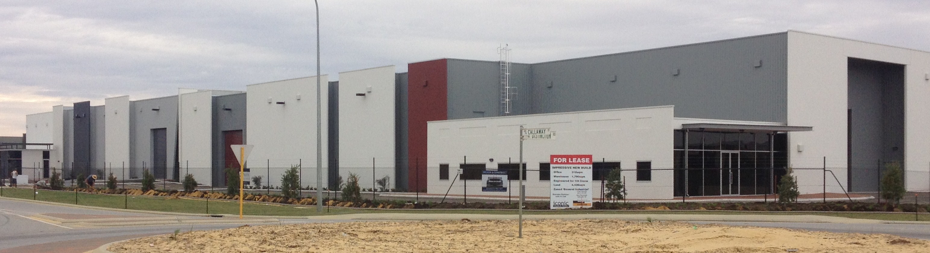 Exterior of large commercial multi-unit warehouse complex, finished in white, grey and red