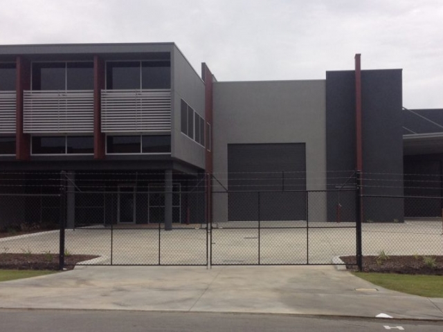 Exterior of securely fenced commercial property painted in shades of grey