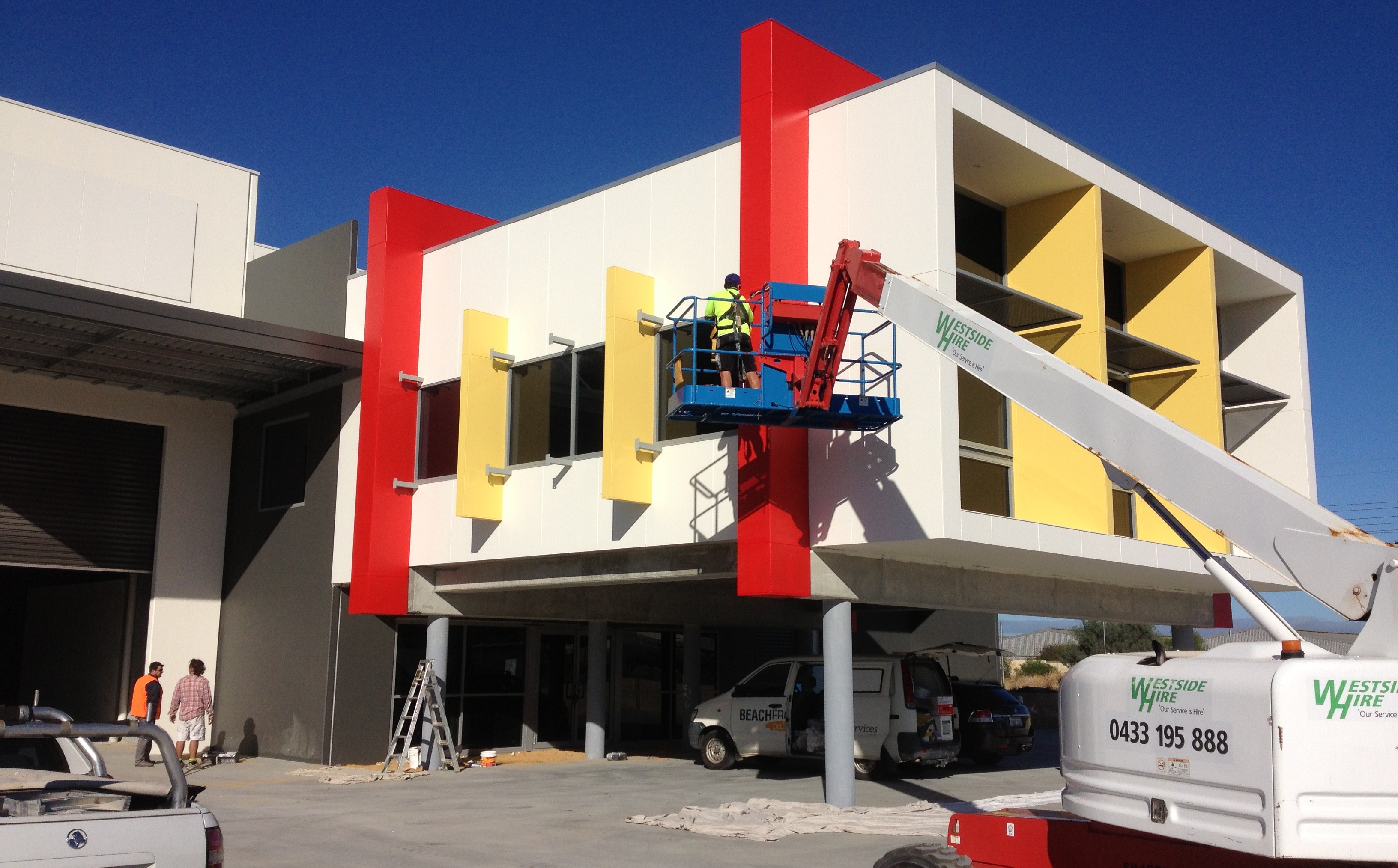 Exterior shot of man painting a commercial building in vibrant colours