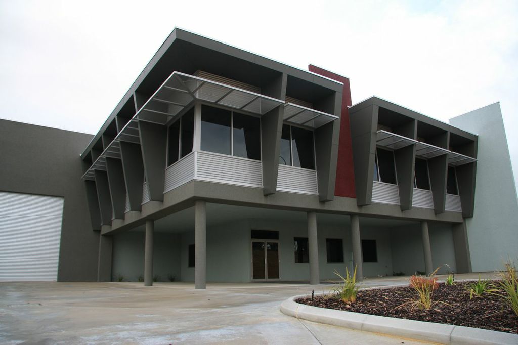 Exterior paint job of large commercial warehouse office, finished in grey with red accents